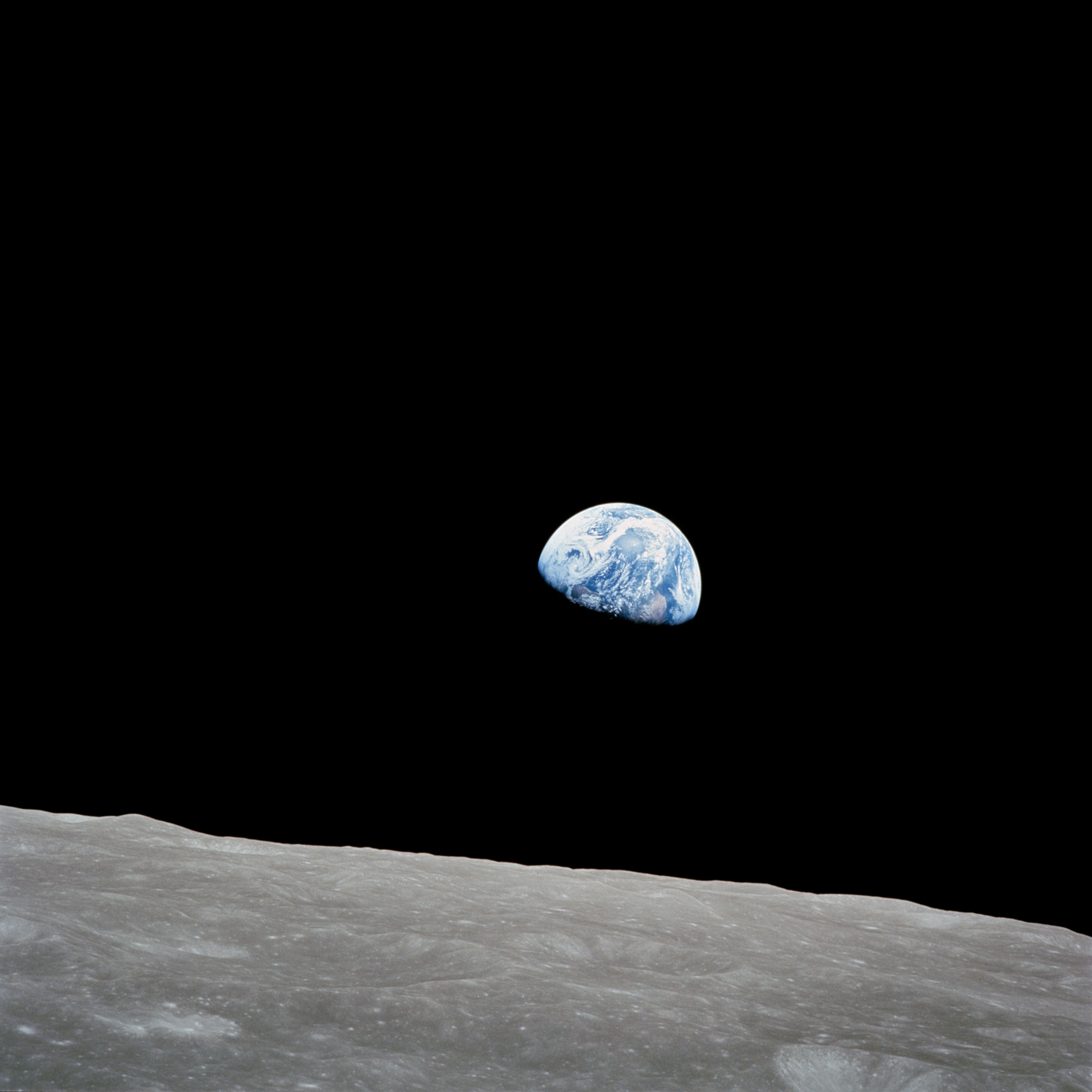 Earthrise — Earth rising over the lunar horizon as photographed by Bill Anders on Apollo 8, December 24, 1968. The blue and white planet hangs above the gray lunar surface against the blackness of space.