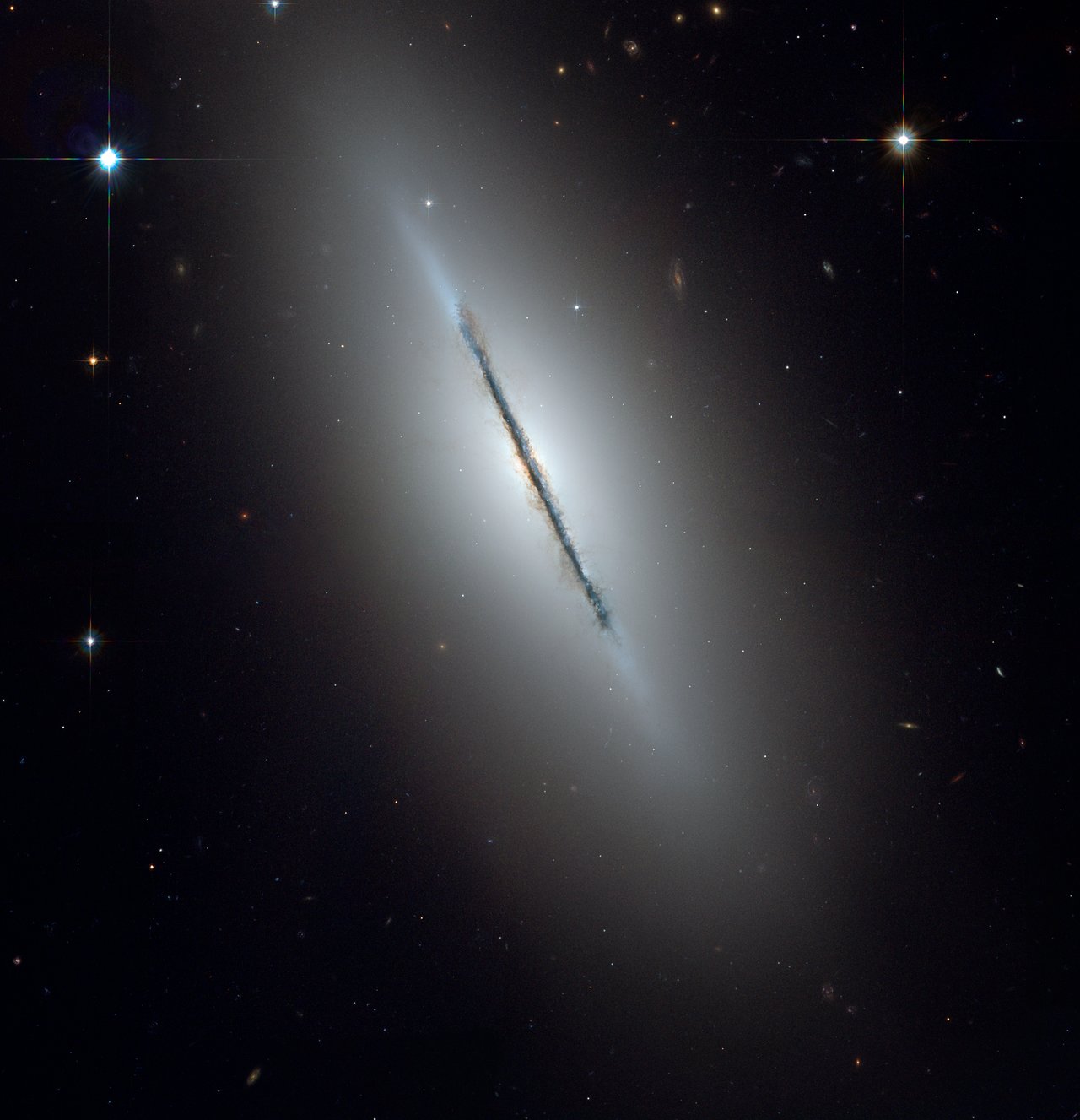 The Spindle Galaxy NGC 5866 in Draco — Hubble edge-on view showing a sharp dust lane bisecting the lenticular galaxy.