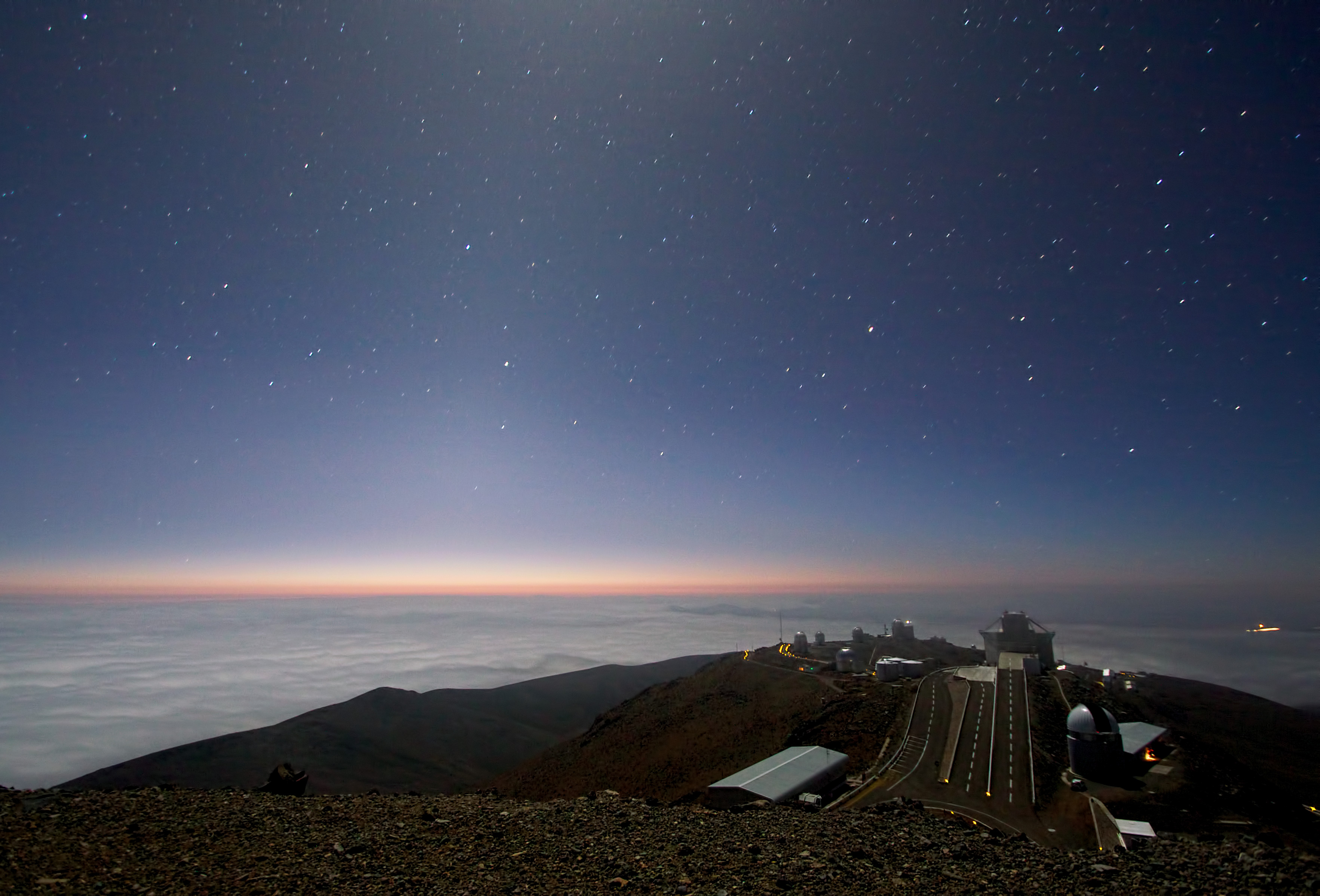 The faint triangular glow of the zodiacal light rising above the domes of ESO's La Silla Observatory under a starry sky